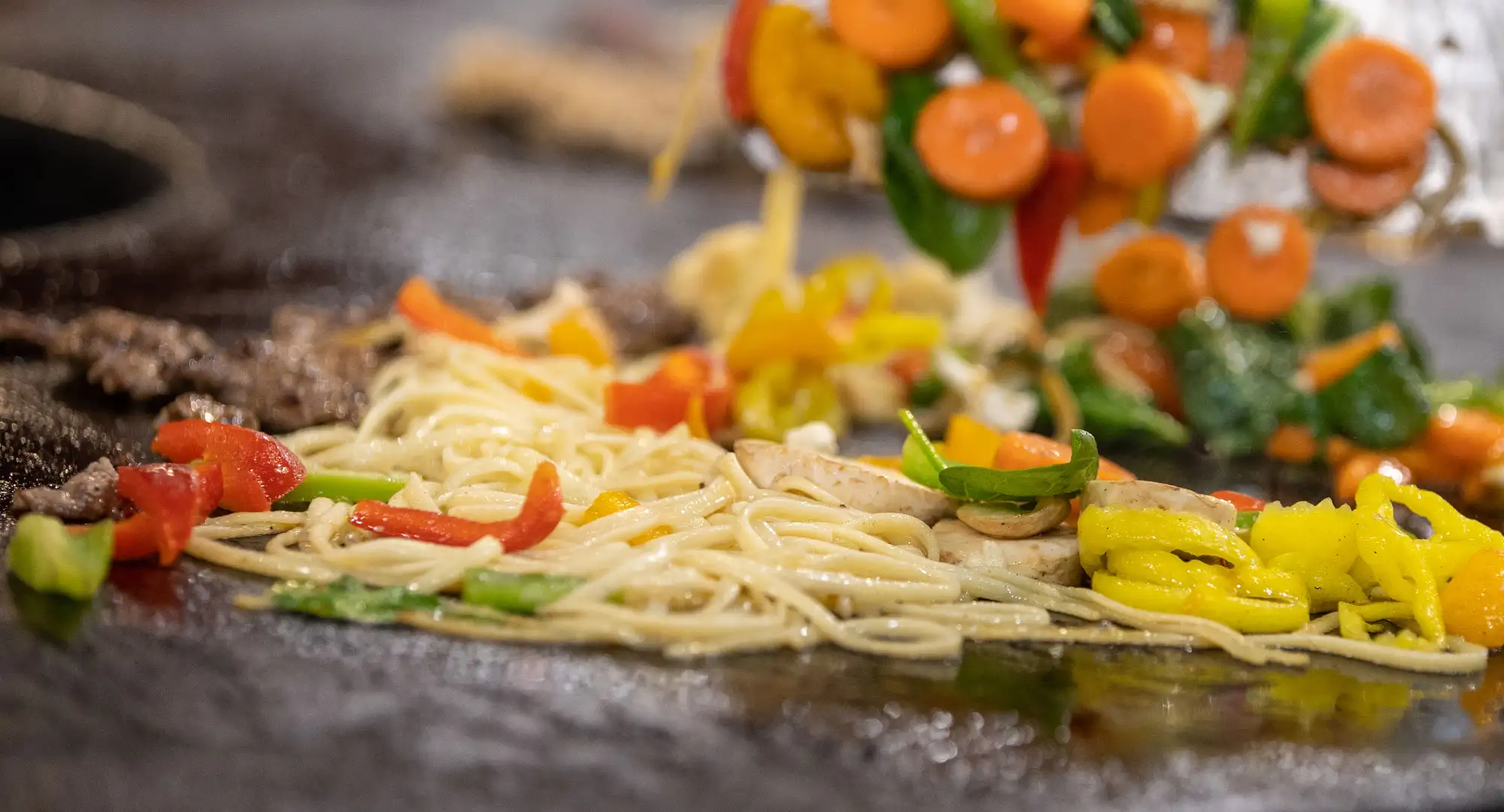 noodles and vegetables cooking on a hot grill