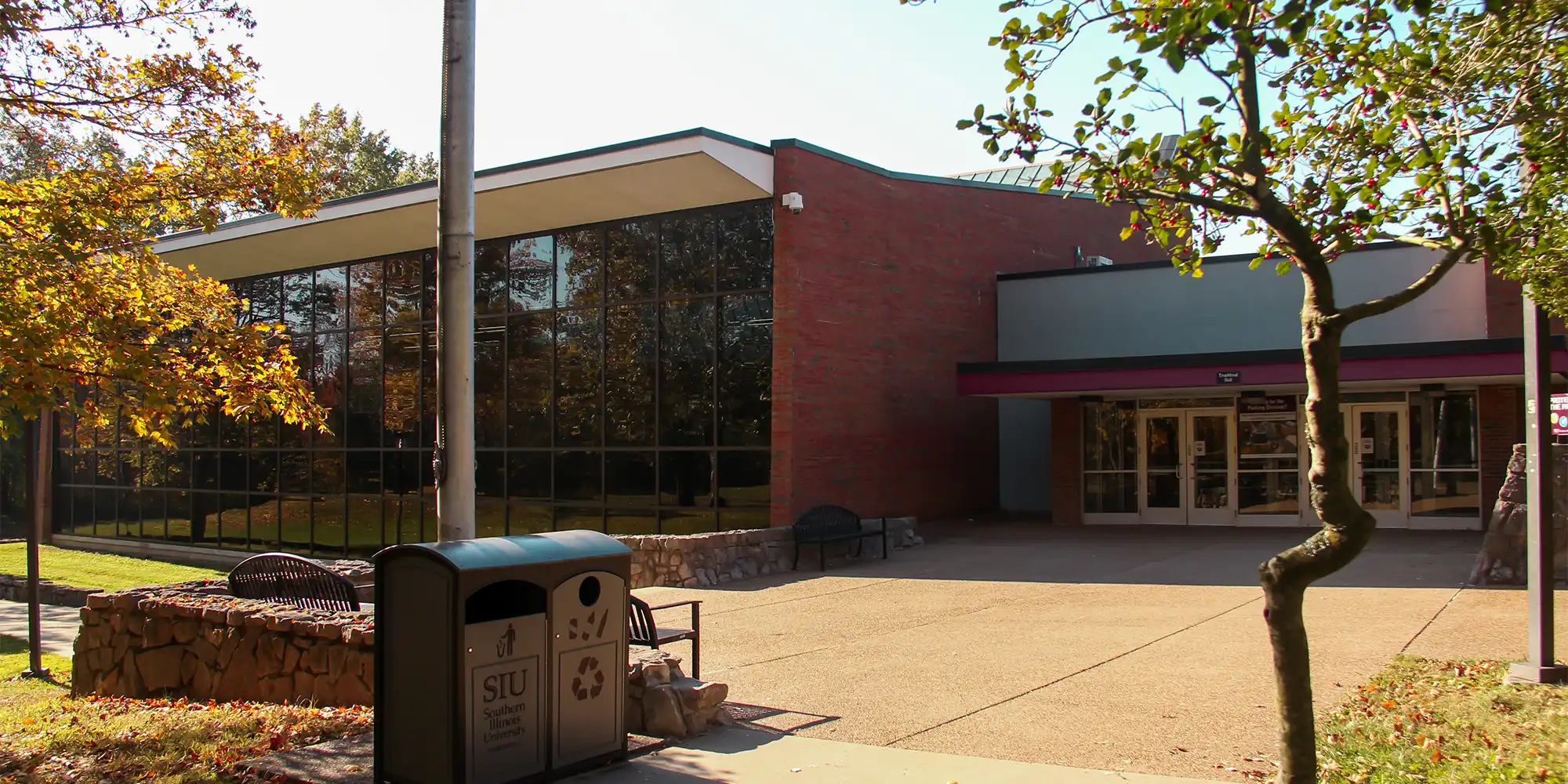 Exterior view of Trueblood Dining Hall, showing its brick facade, large glass windows, and surrounding trees on a sunny day.