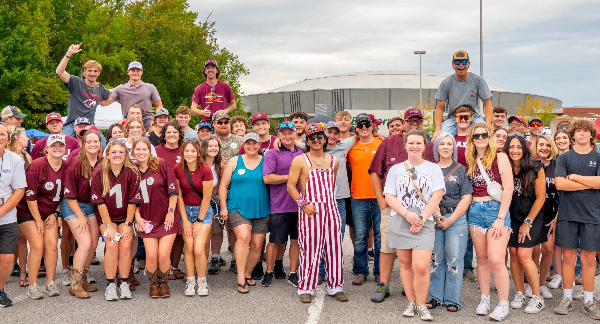 A large group of SIU students, families, and fans pose together outdoors during family weekend event.